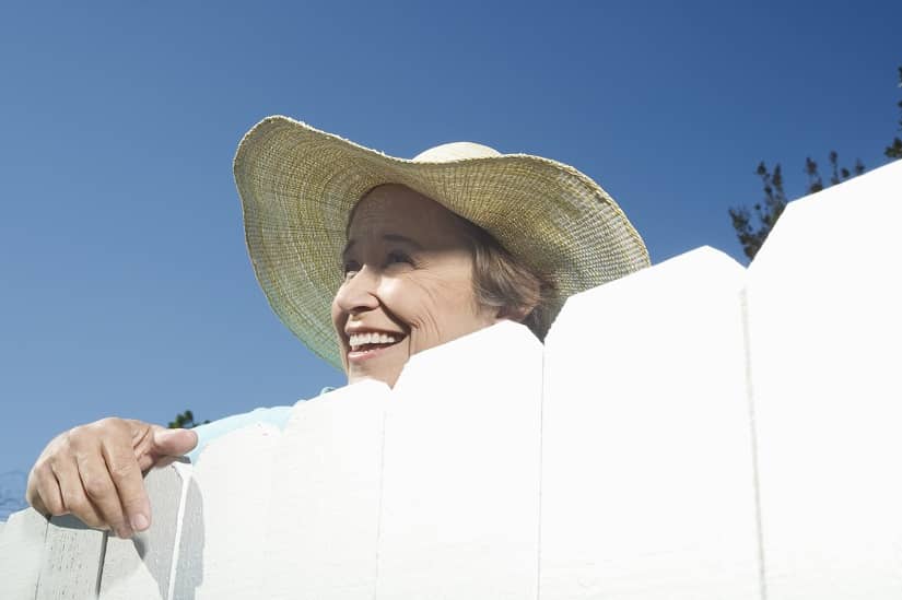 Frau schaut auf den Garten vom Nachbarn 