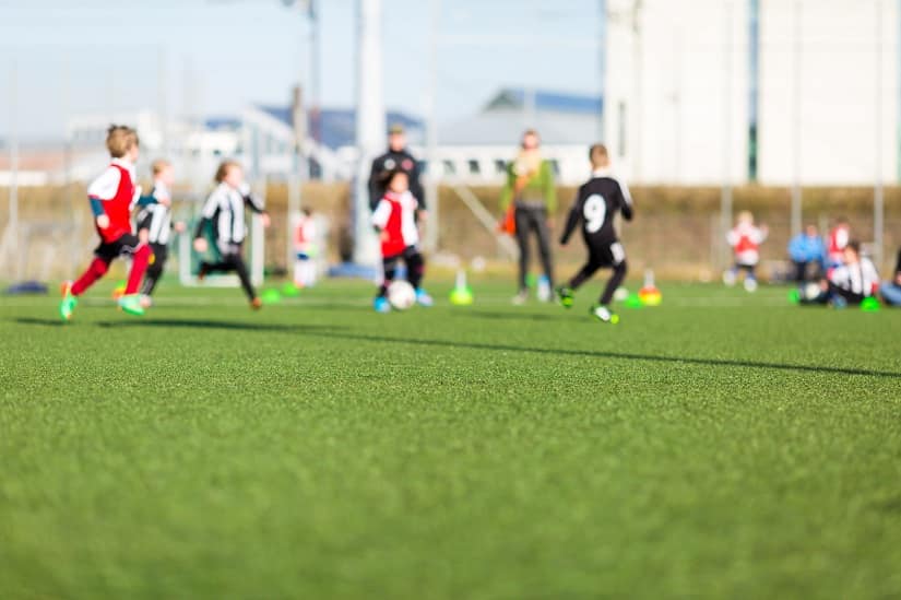 Kinder spielen Fußball auf einem Sport- und Spielrasen