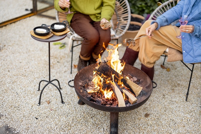 Zwei Frauen sitzen im Herbst im Garten an einer Feuerschale.