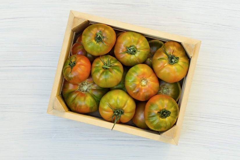 Einige grüne Tomaten in einem Holzschachtel.